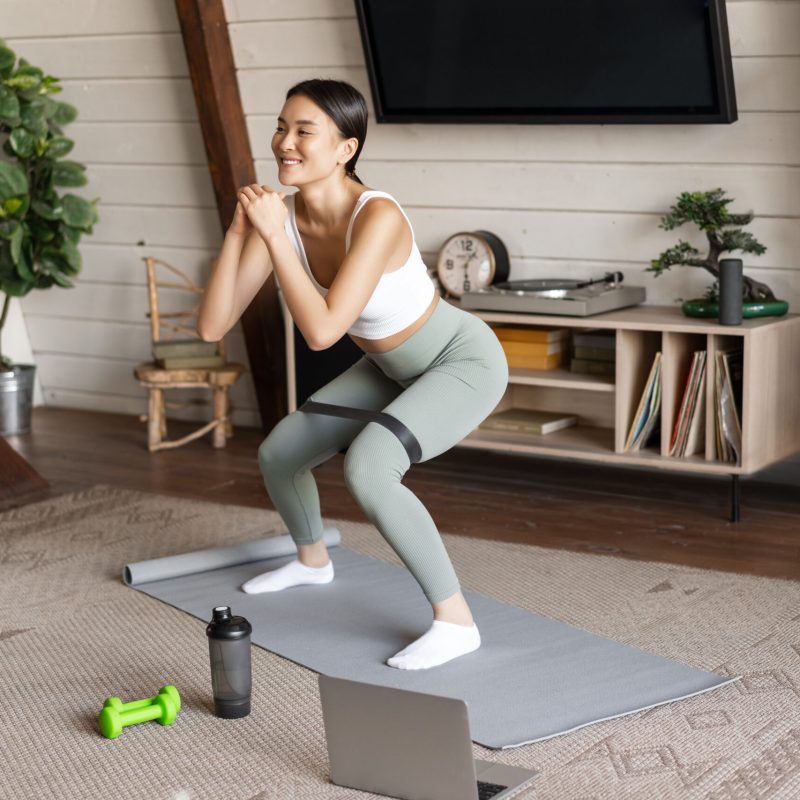 cute-asian-fitness-girl-home-doing-workout-squats-with-stretching-elastic-rope-legs-standing-o with free postpartum fitness guide